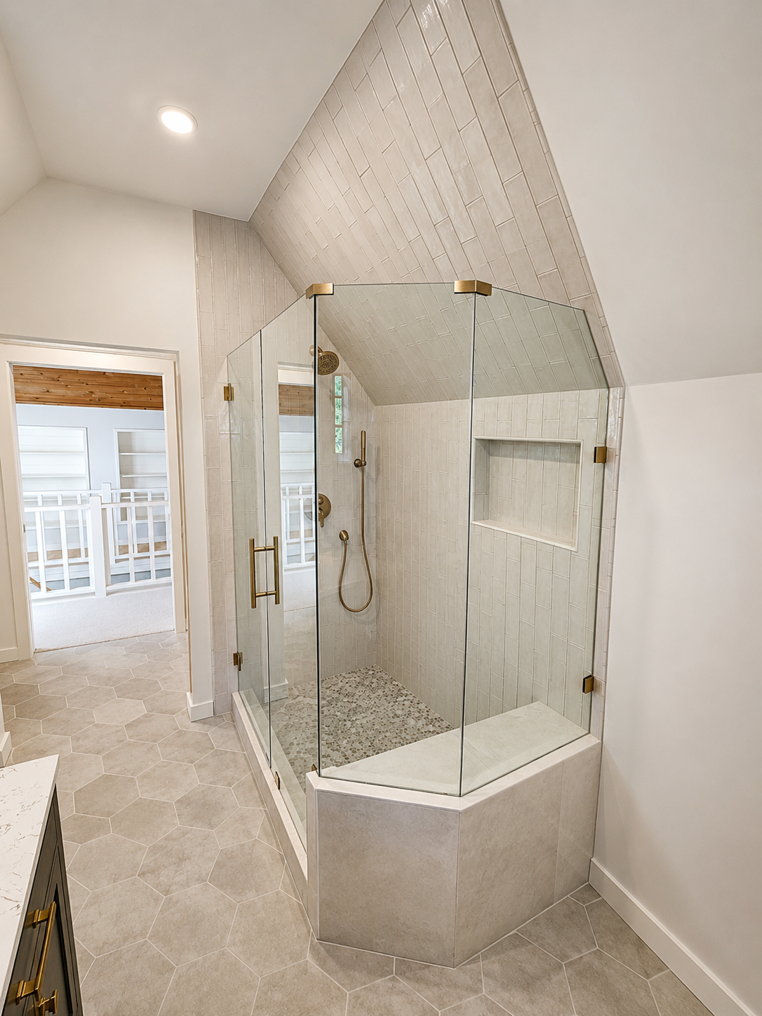 Frameless glass shower with custom tile walls, recessed niche, brass fixtures, and full-height tile installation in Northeast Portland.