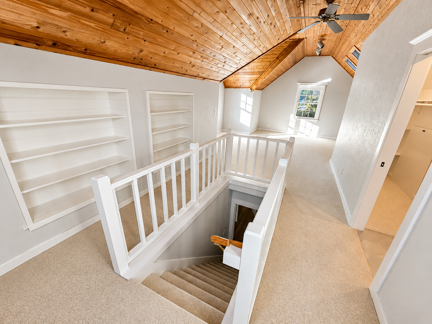 Remodeled primary bedroom featuring custom stair railings, built-in shelving, vaulted ceilings, and updated finishes in Northeast Portland.